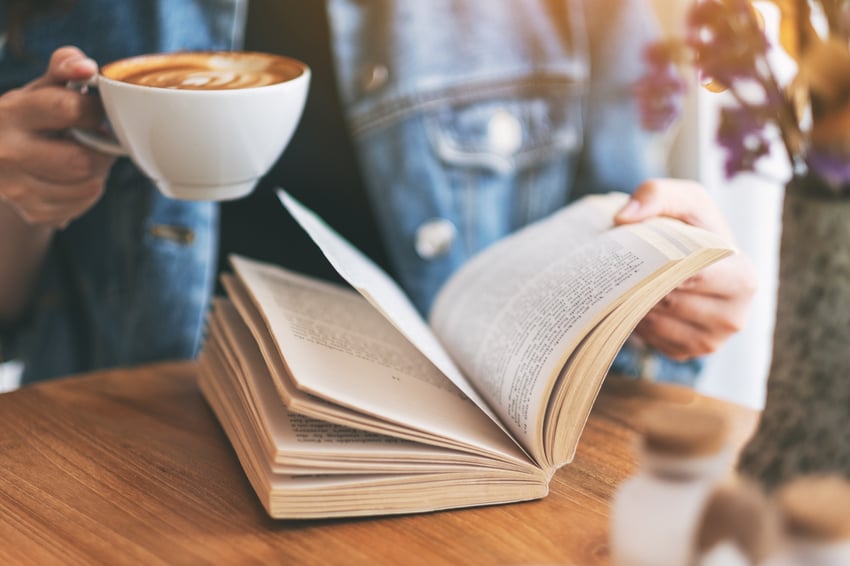 Persoon die een boek leest en koffie drinkt